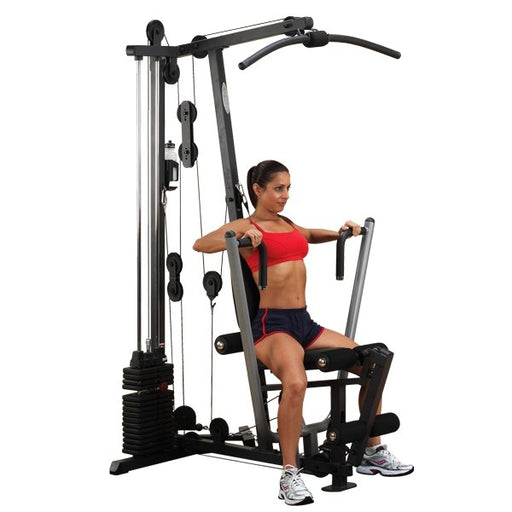 Female athlete performing a chest press on the Body-Solid G1S Multi-Station Home Gym with a 160 lb weight stack, showcasing multi-grip press arms and compact full-body strength training capabilities.