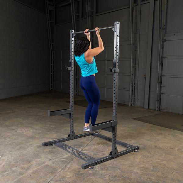 Woman performing chin-ups on the Powerline PPR500 Half Rack by Body-Solid, showcasing upper body strength training in a home gym setup.