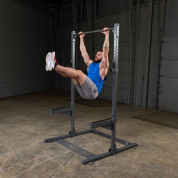 Male athlete performing toes to bar exercise on a pull-up bar, engaging core muscles and demonstrating upper body strength.